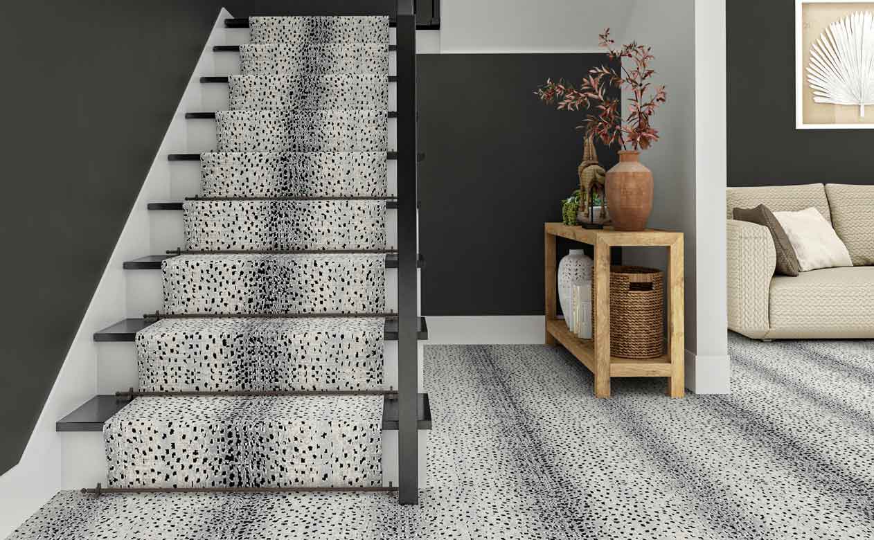 foyer with styled wooden entryway table and staircase with spotted grey carpet