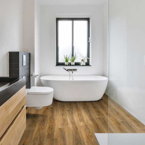 medium wood look flooring in black and white bathroom with large white tub